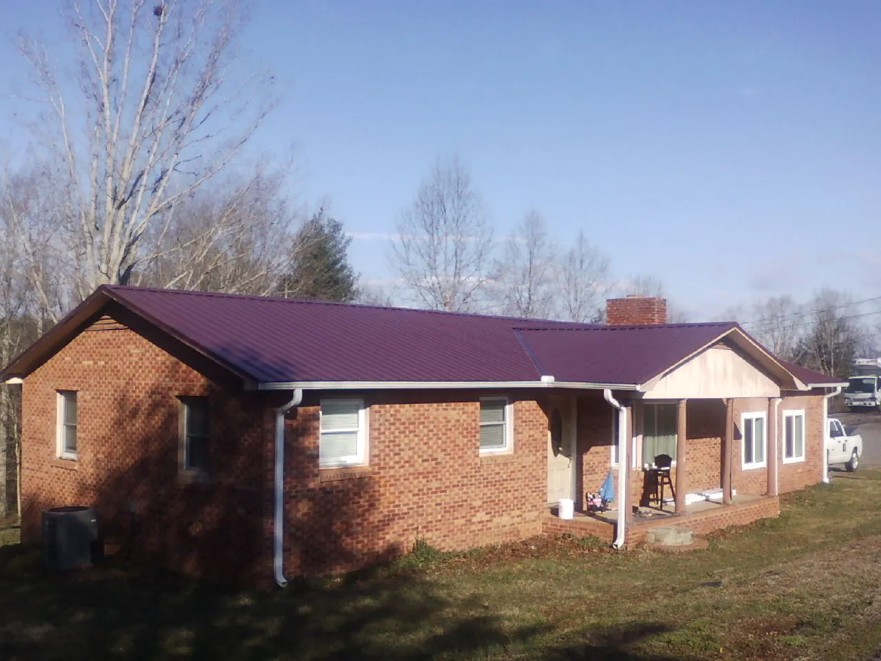 Burgundy metal roof on a brick ranch home with a new addition in Stantonville