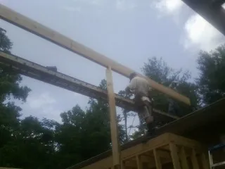 Carpenter setting a ridge beam over a new addition frame — Ice Dam Removal by Roofing Brothers in Stantonville