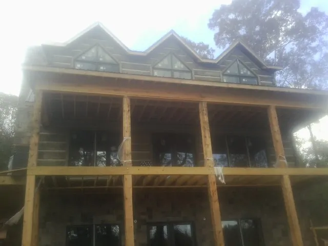Dormers and porch framing on a large log home under construction — Roof Coating work by our crew in Stantonville