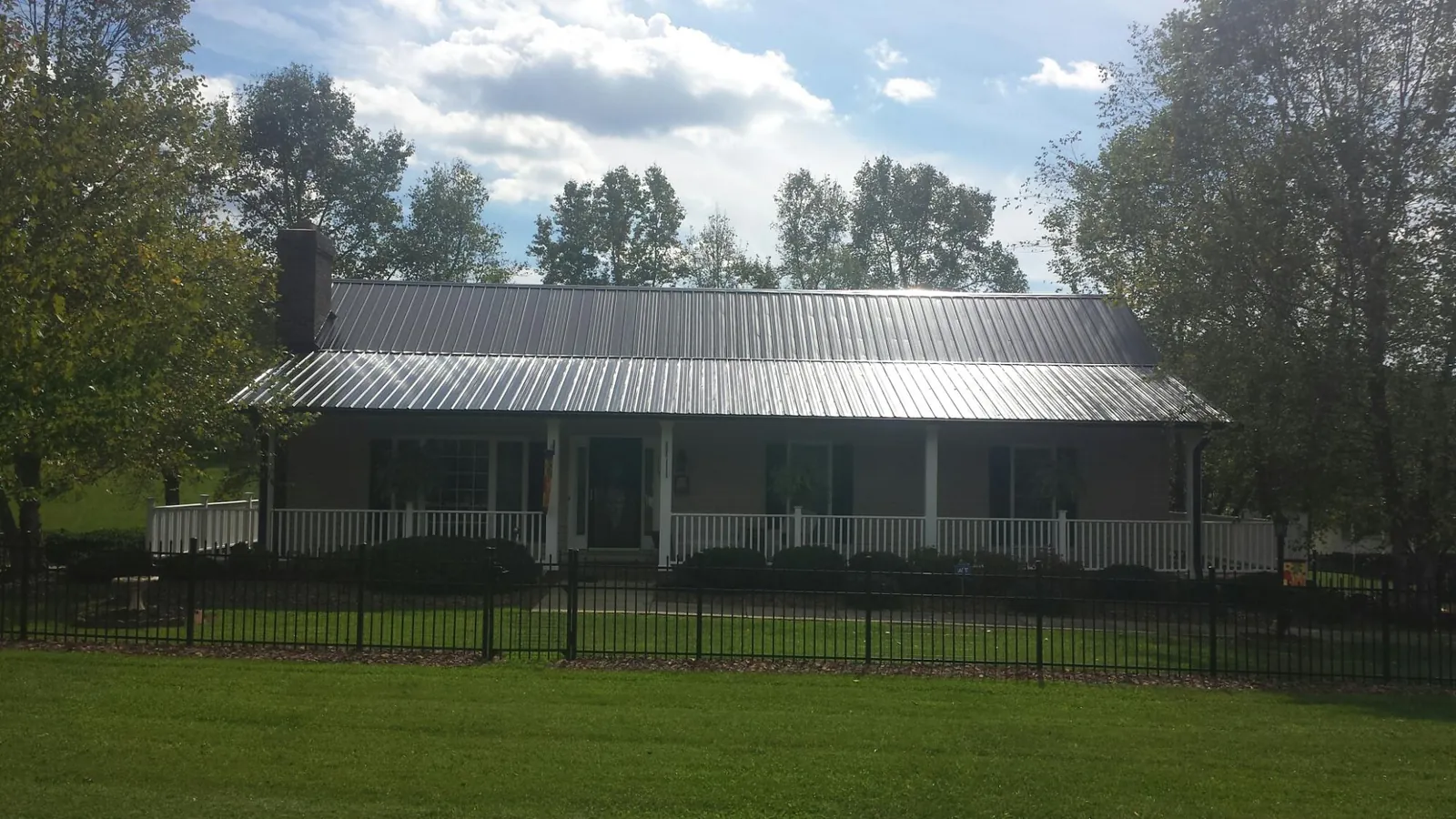 Gray metal roof on a brick ranch with a full width front porch — Gutter Guard Installation work by our crew in Stantonville