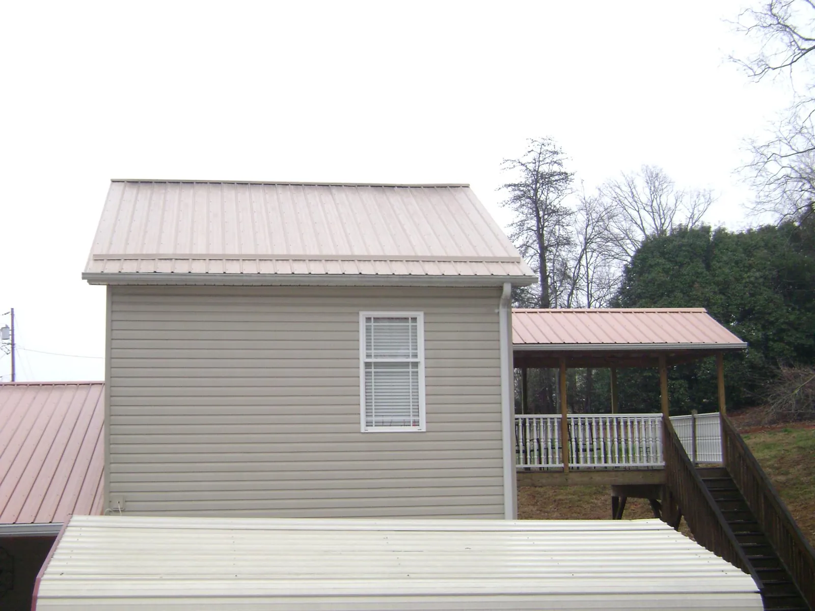 Tan metal roofs on a two story addition and attached porch, from a Roof Replacement job in Stantonville