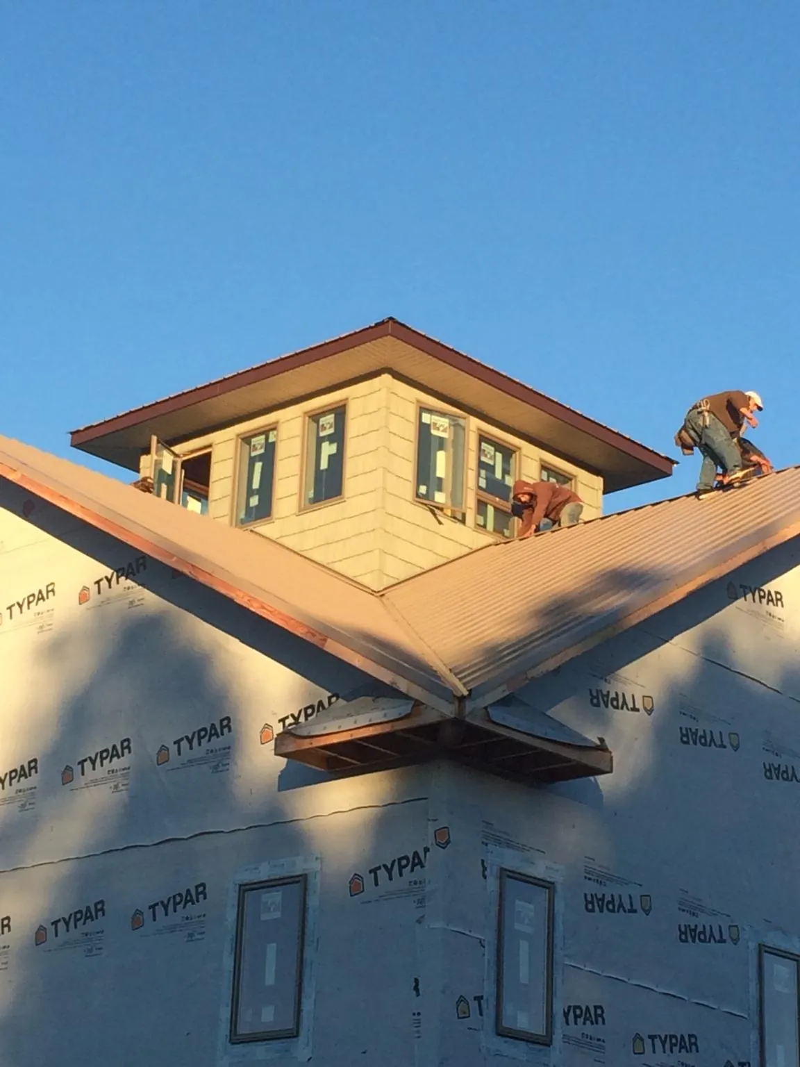 Roofers working around a rooftop cupola on a new metal roof at sunset — Roof Waterproofing in Stantonville by Roofing Brothers